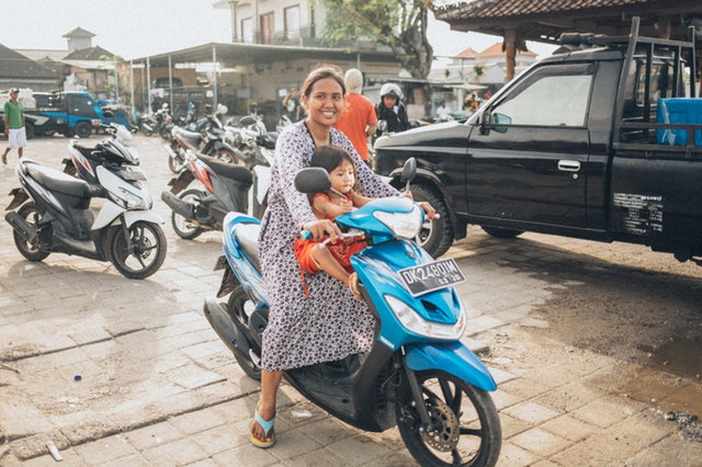 Žena na motorke má pred sebou dieťa bez prilby
