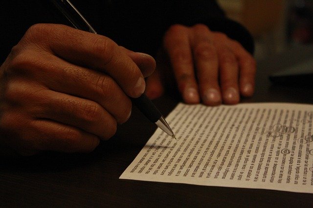 Človek krúžkuje perom chyby na papieri s dlhým textom.jpg